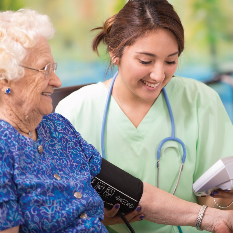 Nurse taking senior woman's blood pressure
